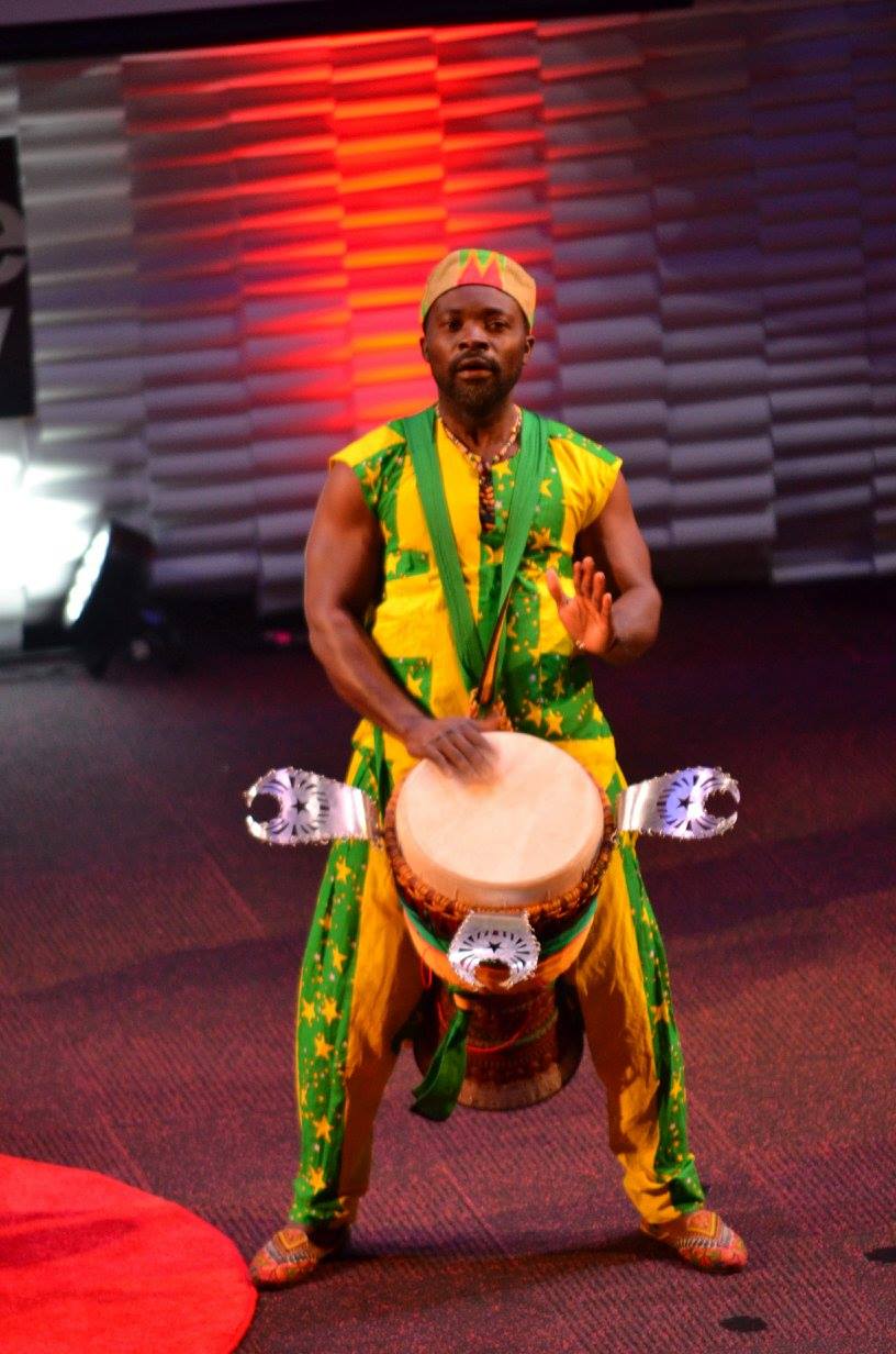 A solo African drummer passionately playing a djembe, with dynamic hand movements and intense focus. The carved drum is detailed and central in the composition. #DjembeLove #SoloDrummer #AfricanPercussion #BeatOfAfrica #TraditionalMusic